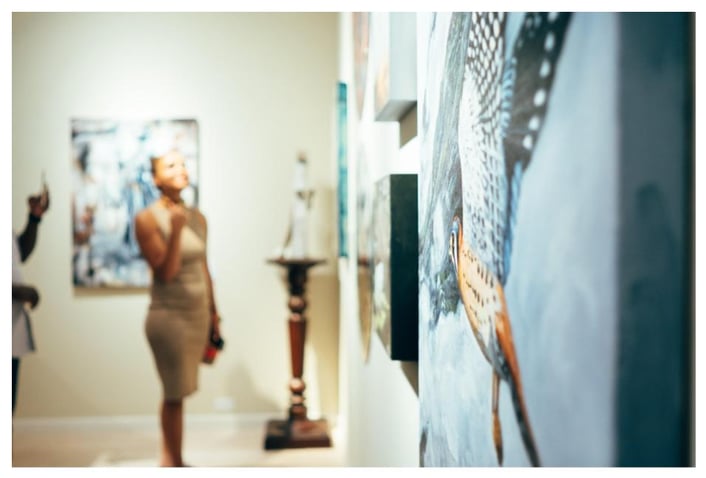 woman standing in gallery in forn tof paintings